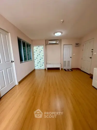 Spacious living room with wooden flooring and modern air conditioning unit.