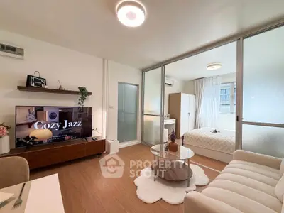 Modern open-plan living room with cozy decor and glass partition to bedroom