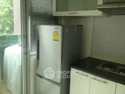 Modern kitchen with sleek fridge and electric stove, adjacent to a bright balcony view.