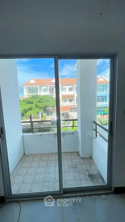 Spacious balcony with sliding glass doors offering a scenic neighborhood view, perfect for relaxation.