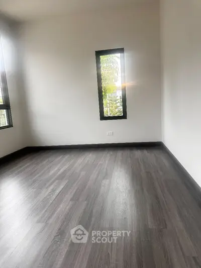 Spacious empty room with large windows and modern flooring, perfect for customization.