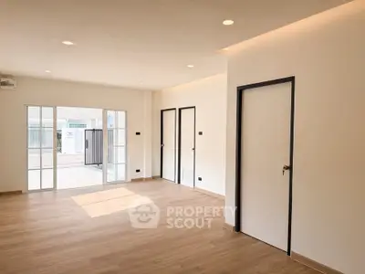 Spacious modern living room with wooden flooring and sliding glass doors leading to a patio.
