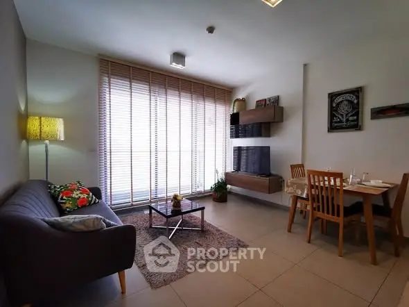 Modern living room with cozy seating and dining area, featuring large windows and stylish decor.