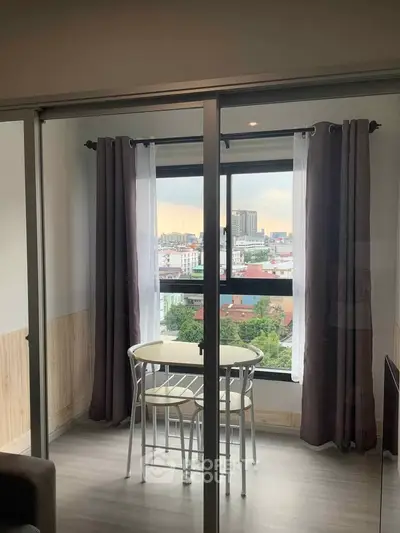 Cozy apartment with city view and small dining area near window.