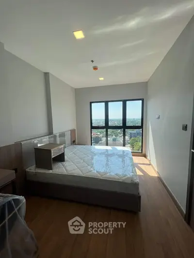 Spacious bedroom with large window offering stunning city views, featuring modern design and natural light.