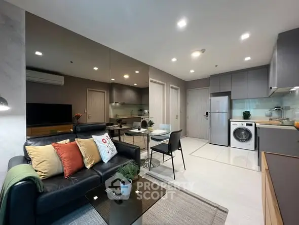 Modern living room with open kitchen, featuring sleek appliances and stylish decor.