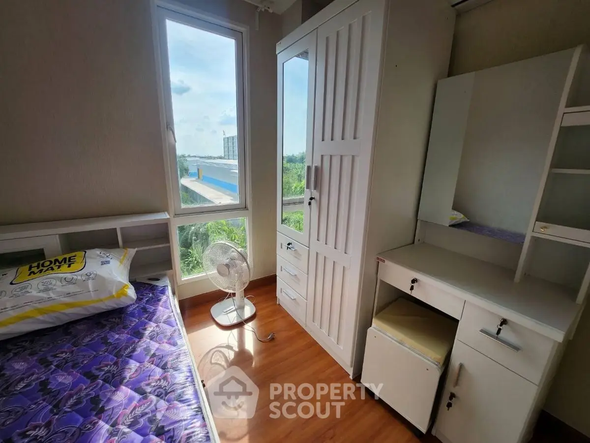 Cozy bedroom with natural light and modern furnishings, featuring a scenic window view.