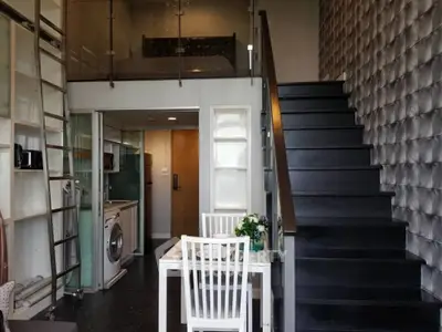 Modern loft apartment with stylish staircase and compact kitchen featuring washing machine.