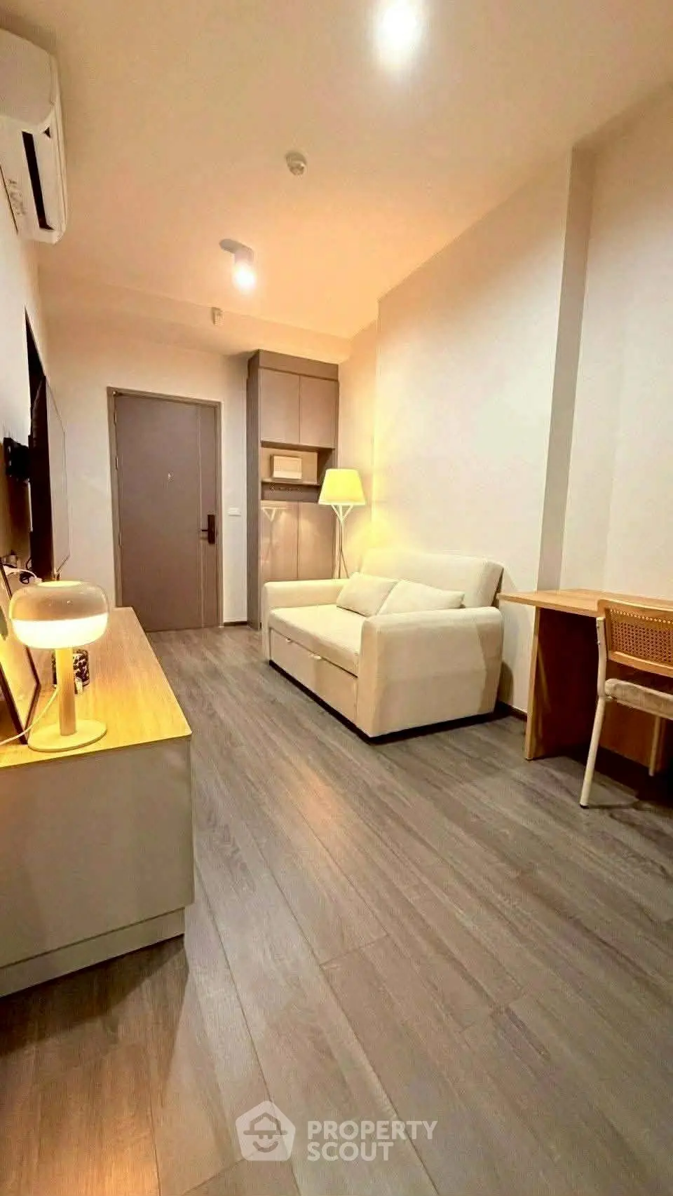 Modern living room with sleek flooring, cozy sofa, and ambient lighting in a stylish apartment.