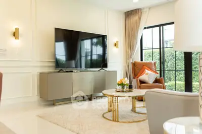 Elegant living room with modern decor, large TV, and garden view through glass doors.