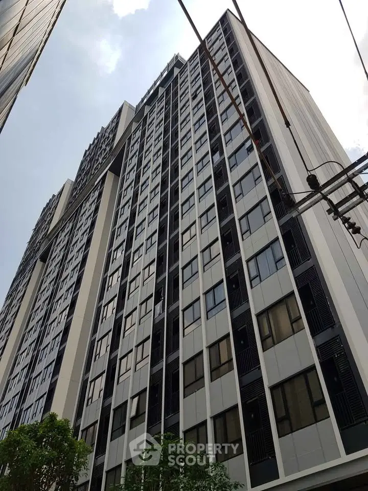 Modern high-rise building with sleek facade and numerous windows, perfect for urban living.