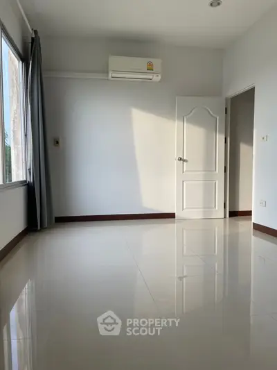 Spacious empty room with glossy tiled floor and air conditioning, perfect for customization.