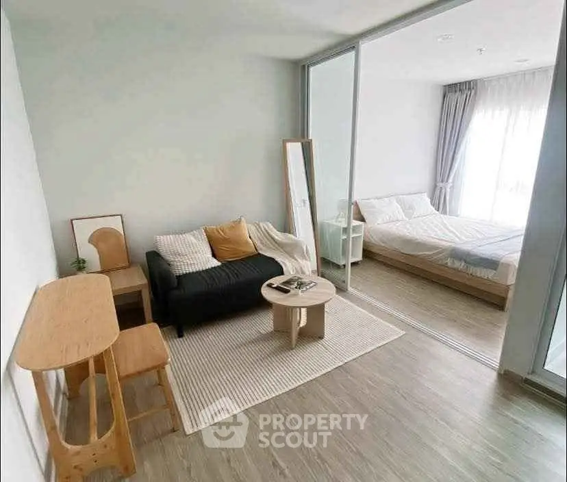 Modern studio apartment with cozy living area and bedroom separated by glass partition.