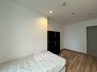 Minimalist bedroom with single bed and wooden flooring in modern apartment.