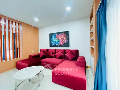 Modern living room with vibrant red sofa and abstract art, perfect for stylish urban living.