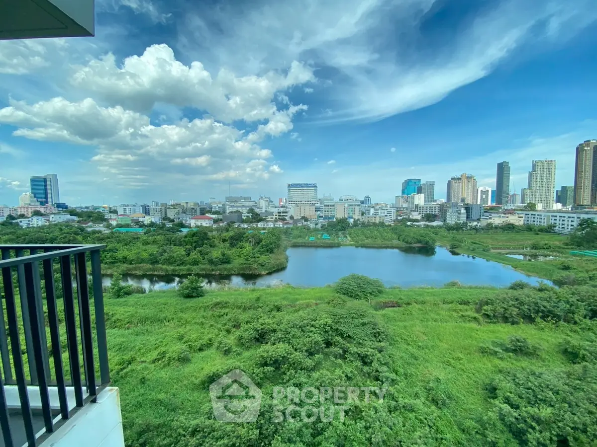 Stunning cityscape view from a high-rise balcony overlooking lush greenery and a serene lake.