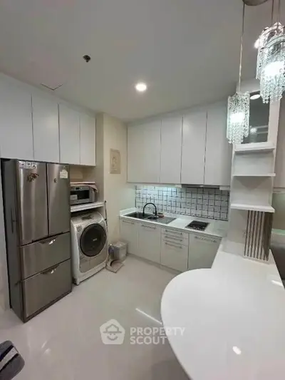 Modern kitchen with sleek white cabinets, stainless steel appliances, and elegant lighting fixtures.