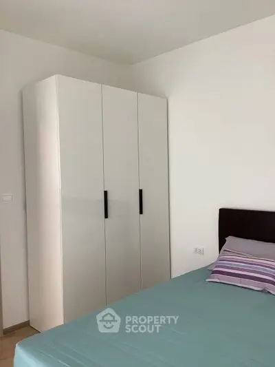 Modern bedroom with sleek white wardrobe and cozy bed setup.