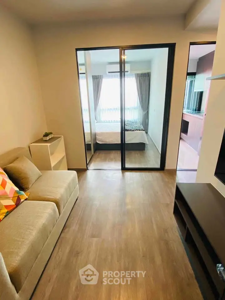 Modern apartment interior with cozy living room and bedroom view, featuring stylish furniture and wooden flooring.