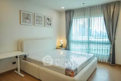 Spacious bedroom with large window and modern decor in a high-rise apartment.
