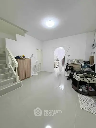Spacious modern living area with sleek staircase and minimalist decor, perfect for family gatherings.