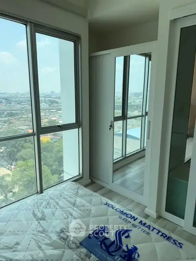 Bright bedroom with large windows offering stunning city views and a comfortable mattress.