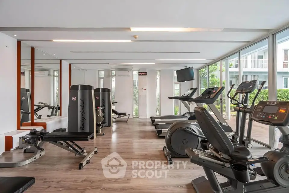 Modern gym with state-of-the-art fitness equipment and large windows for natural light.