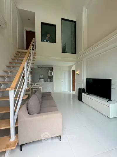 Spacious modern living room with high ceiling and stylish staircase in a contemporary home.
