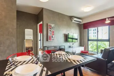 Modern living room with stylish decor and dining area, featuring large windows and natural light.