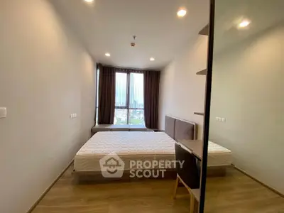 Spacious modern bedroom with large window and city view, featuring minimalist design and ample natural light.