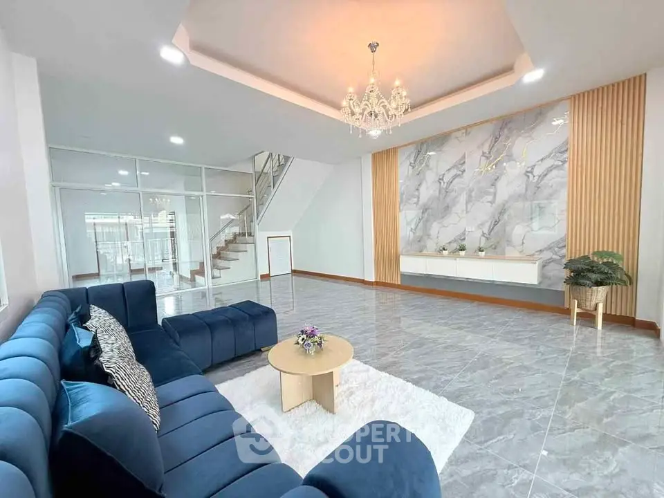 Spacious modern living room with elegant chandelier and stylish blue sofa
