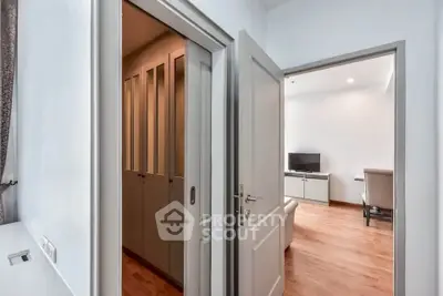 Modern apartment interior with wooden flooring and open doors leading to a cozy living room.