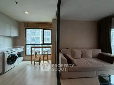 Modern apartment with open layout, featuring a cozy living area and a compact kitchen with washing machine.