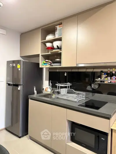 Modern kitchen with sleek cabinetry, stainless steel fridge, and built-in microwave for stylish urban living.
