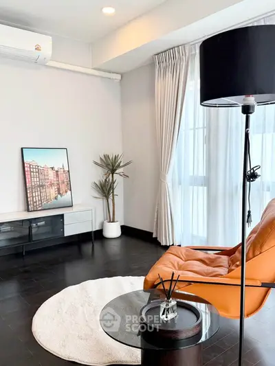Modern living room with stylish decor, featuring a leather chair, floor lamp, and large window with curtains.