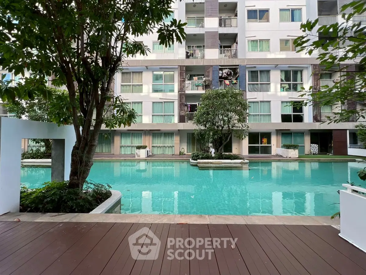 Luxurious apartment building with serene pool and lush greenery