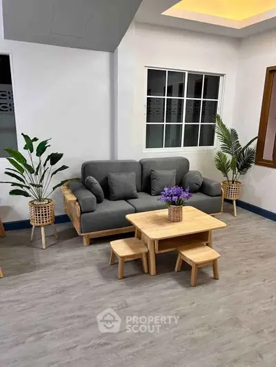 Stylish living room with modern gray sofa, wooden coffee table, and lush indoor plants.
