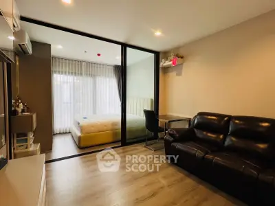 Modern studio apartment with glass partition, cozy living area, and stylish bedroom.