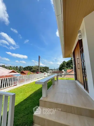 Charming house with spacious balcony and scenic view of rooftops and blue sky.