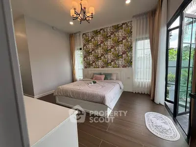Charming bedroom with floral accent wall and elegant chandelier, featuring large windows for natural light.