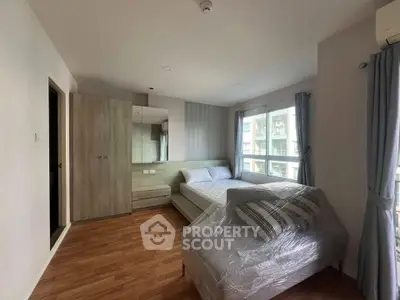 Spacious bedroom with modern furnishings and large windows for natural light.