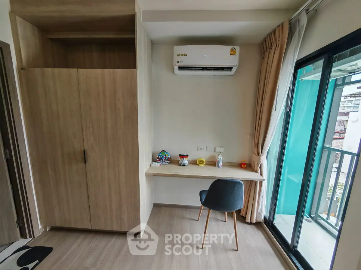 Modern study area with balcony view, featuring sleek desk and chair, air conditioning, and ample storage.
