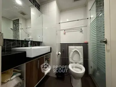 Modern bathroom with sleek fixtures and glass shower enclosure in a contemporary home.