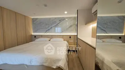 Luxurious bedroom with elegant wood paneling and marble accent wall, featuring a cozy double bed.