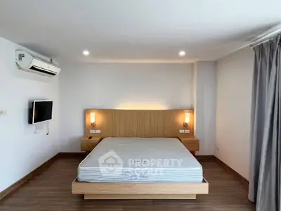 Modern minimalist bedroom with wooden flooring and wall-mounted TV