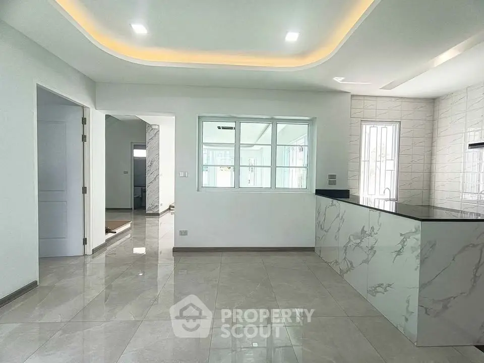 Modern open layout kitchen with marble countertops and sleek lighting
