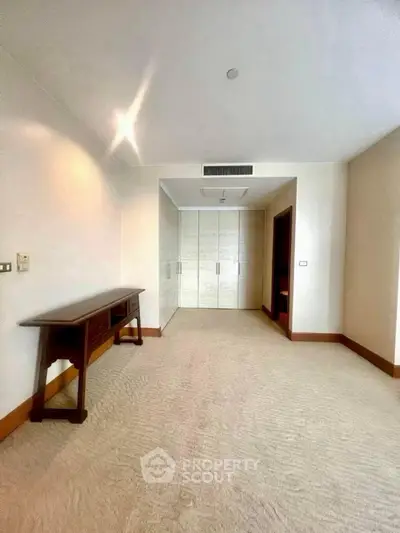 Spacious bedroom with built-in wardrobe and elegant carpet flooring.