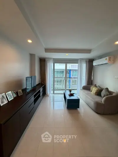 Spacious modern living room with sleek furniture and large window offering natural light.
