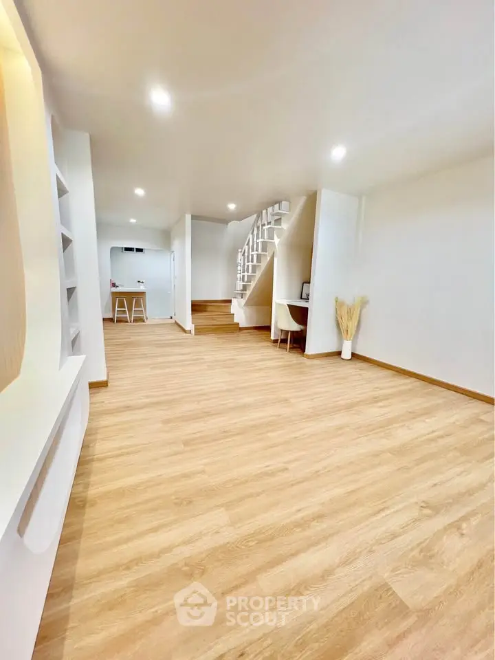 Spacious modern living room with wooden flooring and unique staircase design.