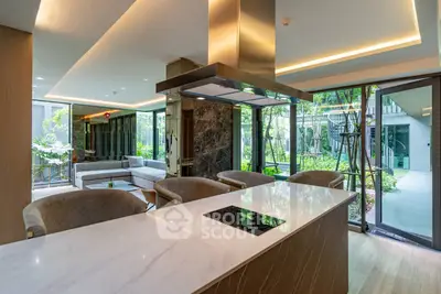 Luxurious open-plan kitchen and living area with garden view, featuring modern island and sleek design.